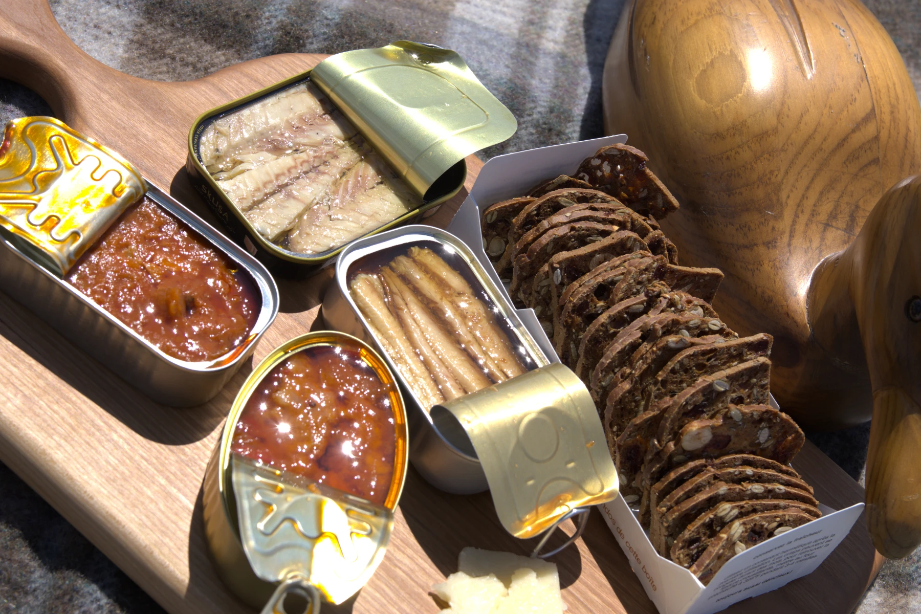 Four opened tins of fish on chartuterie board