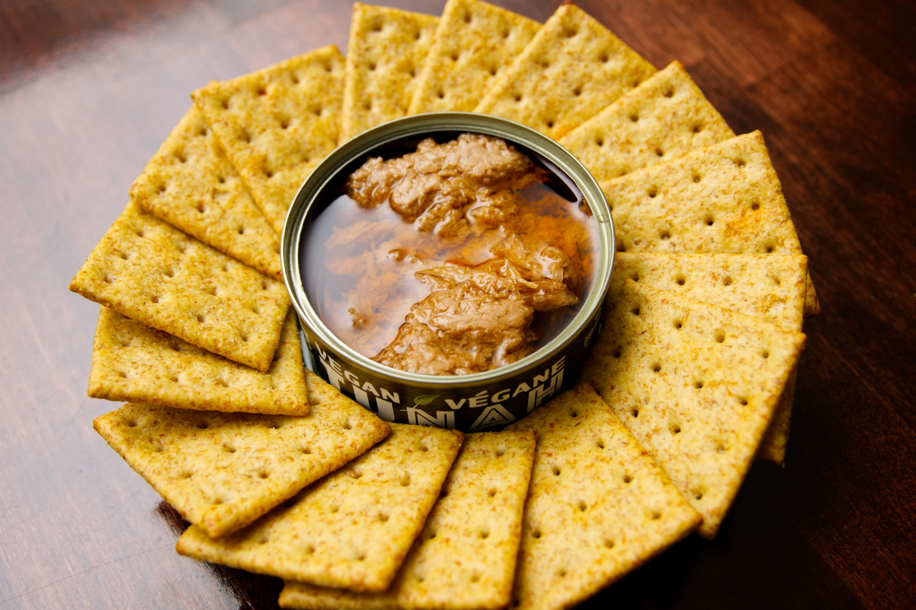 Opened can of tunah with a wreath of crackers surrounding the can.